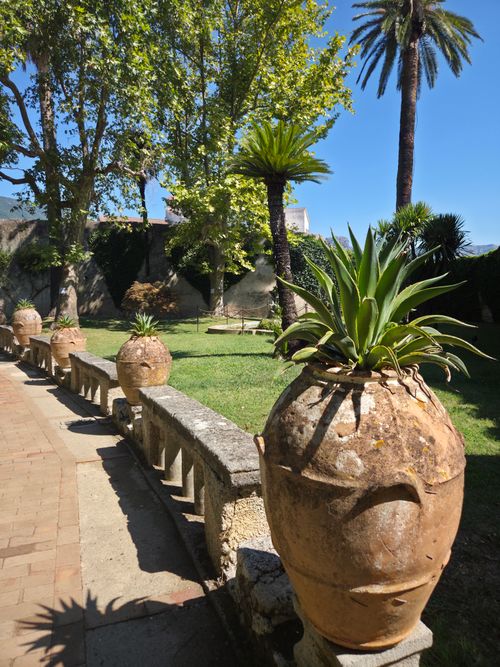 Free Serene garden in Campania featuring terracotta pots, palm trees, and lush greenery on a sunny day. Stock Photo