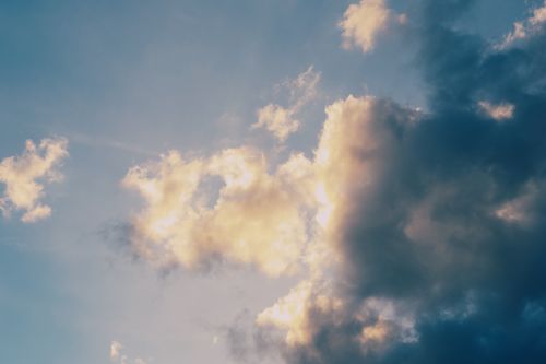Free Captivating view of sunlit clouds against a serene blue sky during twilight. Perfect for nature enthusiasts. Stock Photo