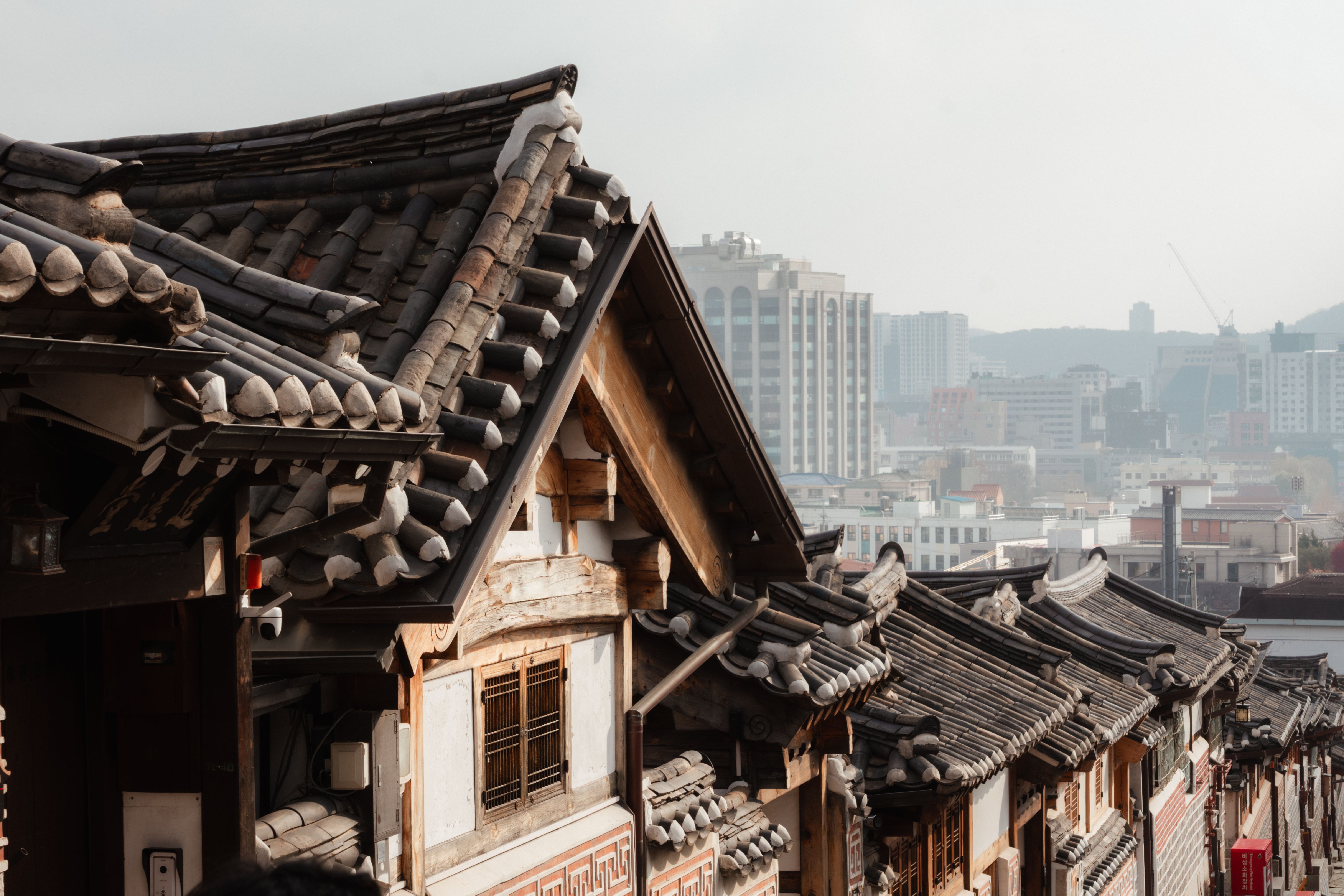 Traditional hanok roofs overlooking a modern cityscape, blending heritage and contemporary architecture.
