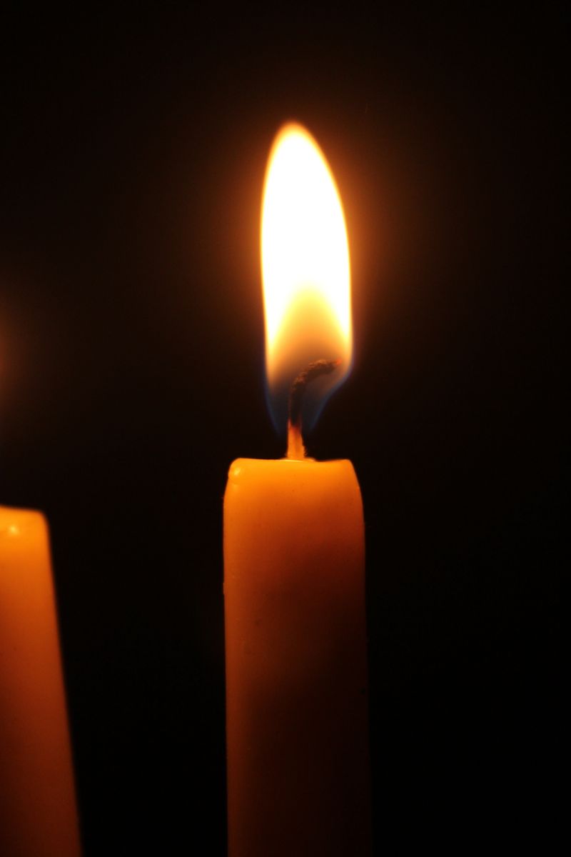 A single candle flame burning in the dark