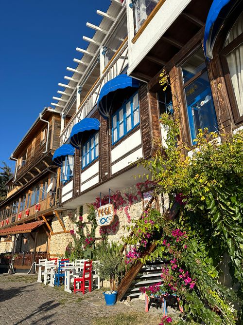Free Sunny day view of a charming wooden facade building on a cobblestone street with vibrant flowers. Stock Photo