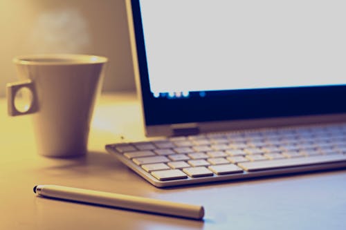 White Mug Beside Apple Keyboard