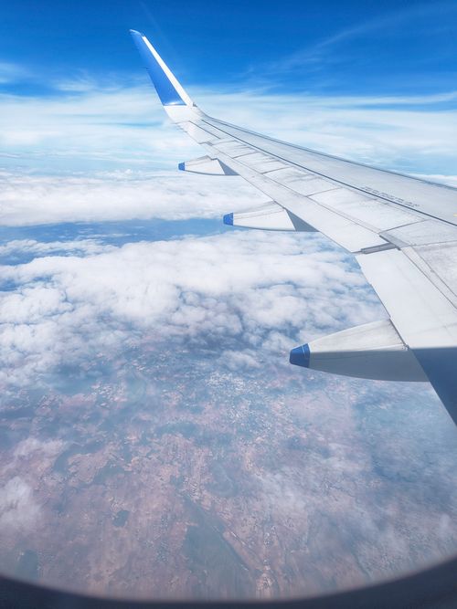 Free View from airplane window showing wing and clouds below during daylight flight. Stock Photo