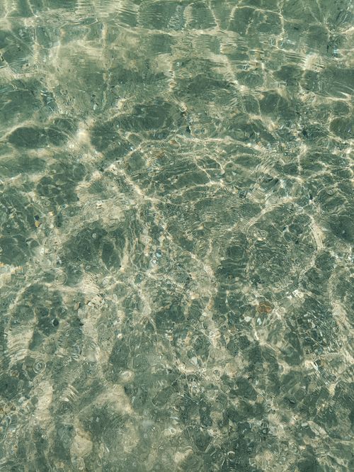 Free A captivating view of sunlight reflecting on clear water, creating mesmerizing patterns. Stock Photo