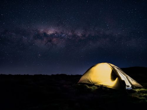 Free Brightly lit yellow tent beneath a stunning Milky Way nightscape in South Africa. Stock Photo