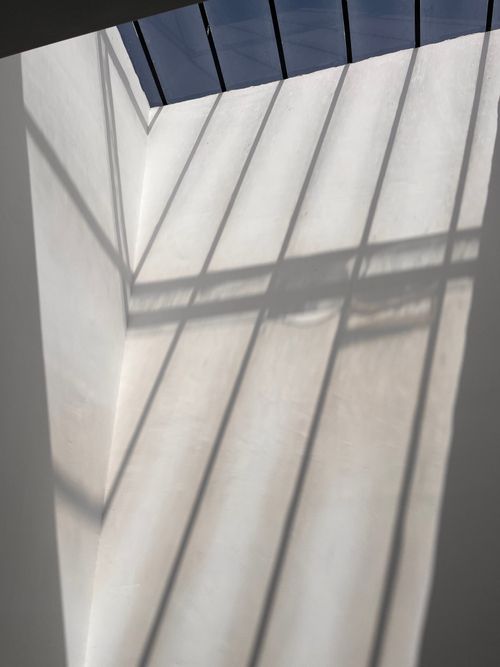 Free Sunlight creates abstract patterns on a modern indoor architectural wall, offering a minimalist and artistic view. Stock Photo