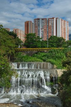 A vibrant urban waterfall beneath high-rise buildings in Medellín, Colombia.