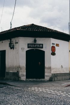 Vintage corner building in Antigua, Guatemala featuring Fujifilm signage and rustic cobblestone street.