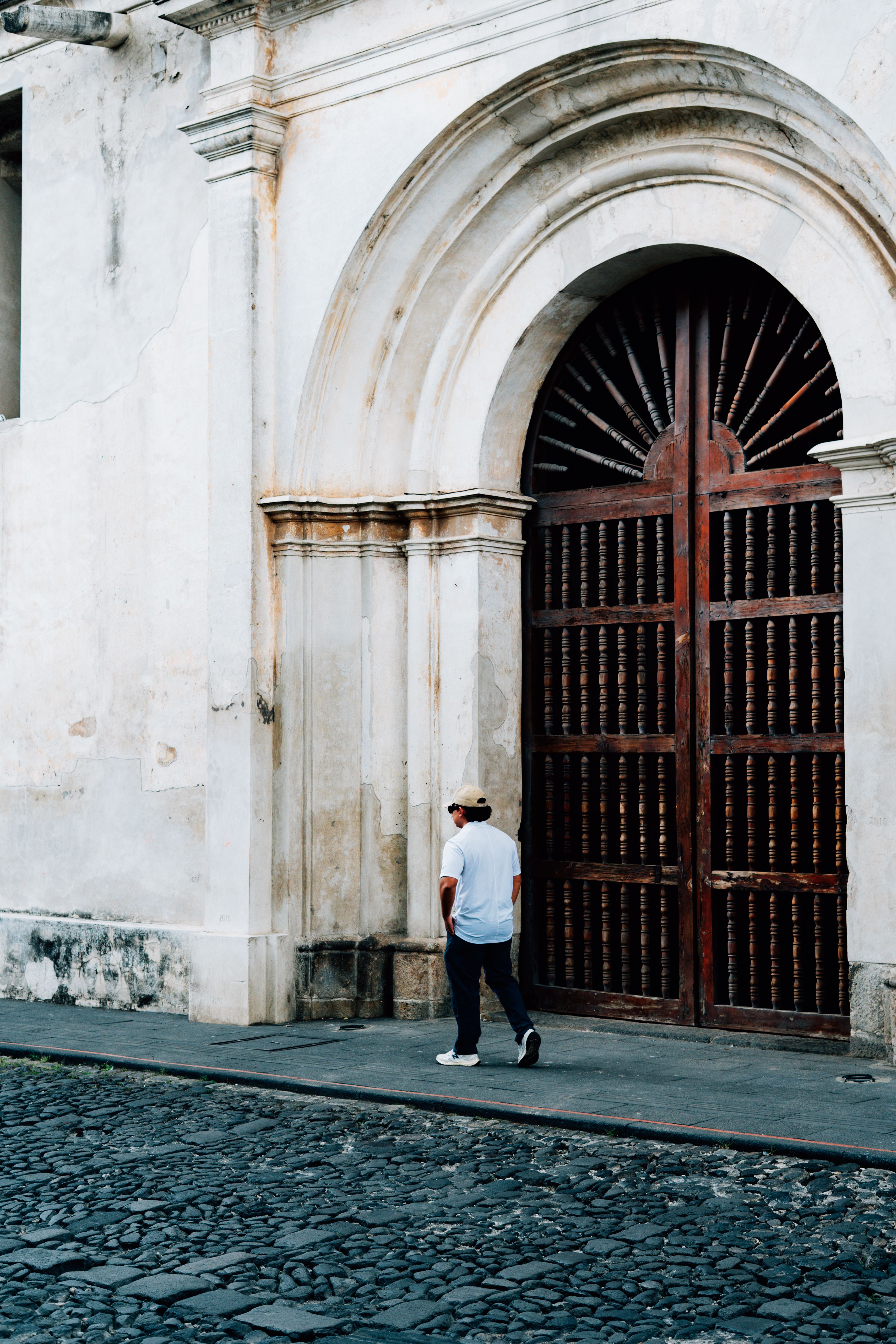 A person walks past a historic doorway in Antigua, Guatemala, showcasing colonial architecture.