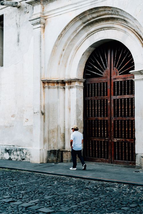 Free A person walks past a historic doorway in Antigua, Guatemala, showcasing colonial architecture. Stock Photo