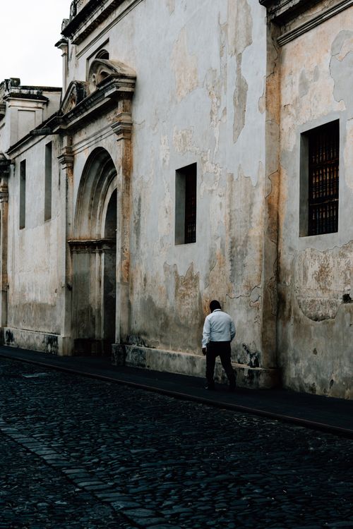 Free A solitary man walks along a historic cobblestone street in Antigua, Guatemala. Stock Photo