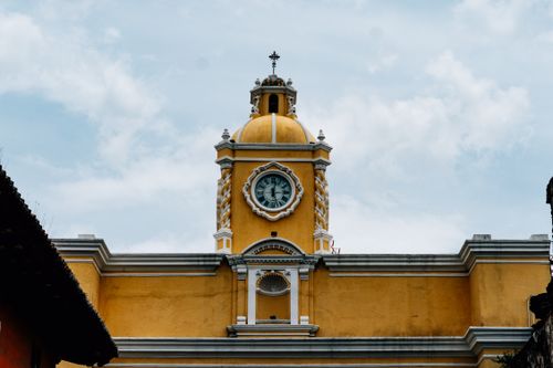 Free The vibrant yellow clock tower in Antigua, Guatemala captures historic colonial architecture. Stock Photo