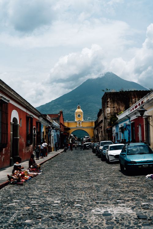 Free Colorful colonial street in Antigua Guatemala with Arco de Santa Catalina and volcano backdrop. Stock Photo