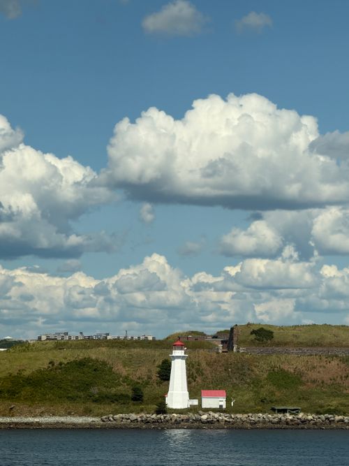 Free Lighthouse by the ocean under a dramatic sky with fluffy clouds, captured in Halifax, Nova Scotia. Stock Photo