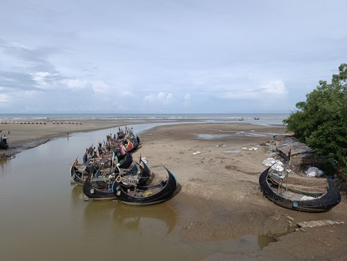 Free Traditional fishing boats rest on a sandy beach under a bright sky. Stock Photo