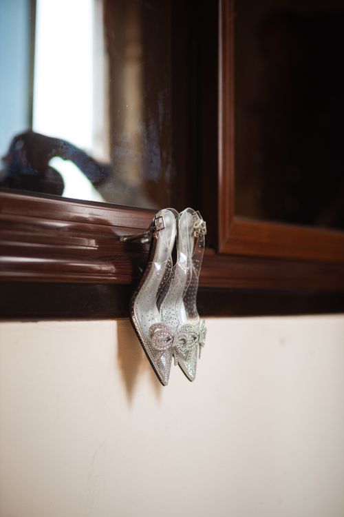 Free A pair of sparkling glass slipper-style shoes elegantly displayed on a window sill indoors. Stock Photo