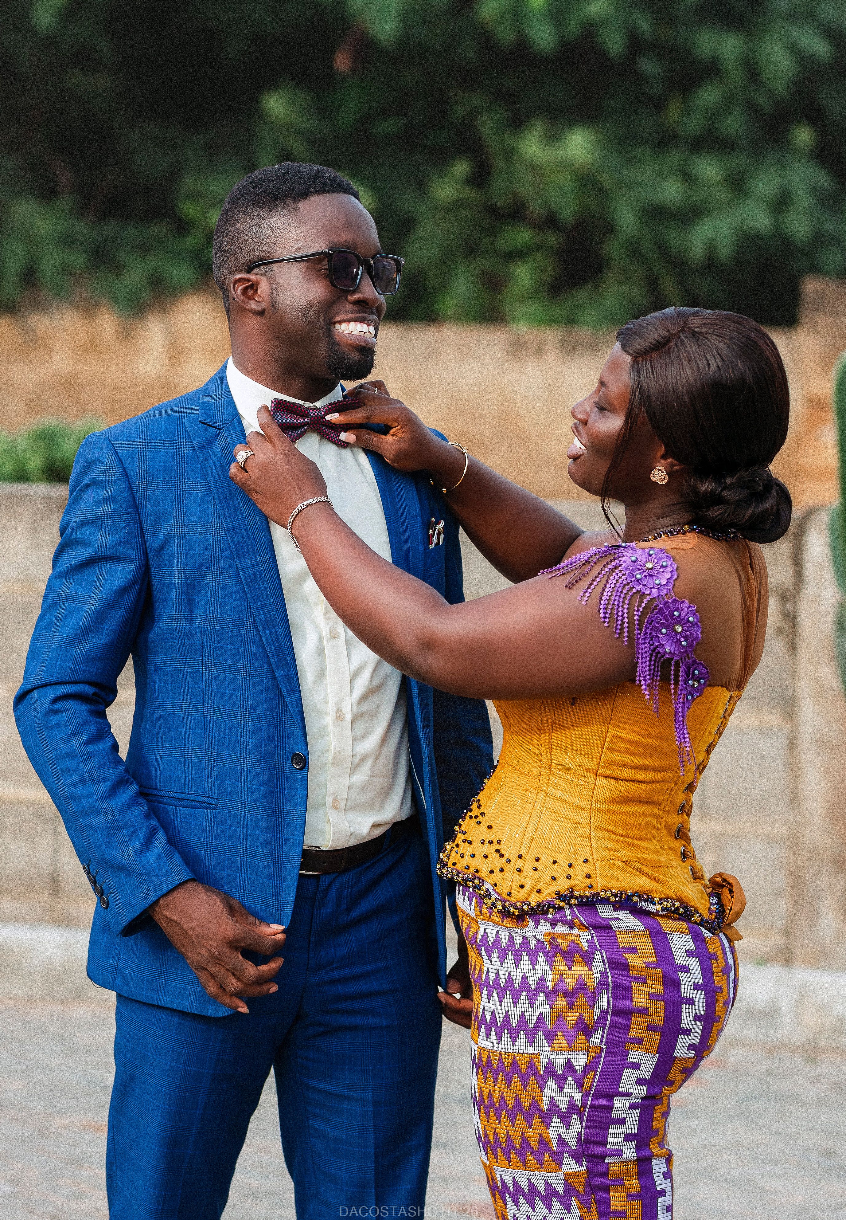Stylish couple dressed in traditional vibrant clothing enjoying a joyful moment outdoors.
