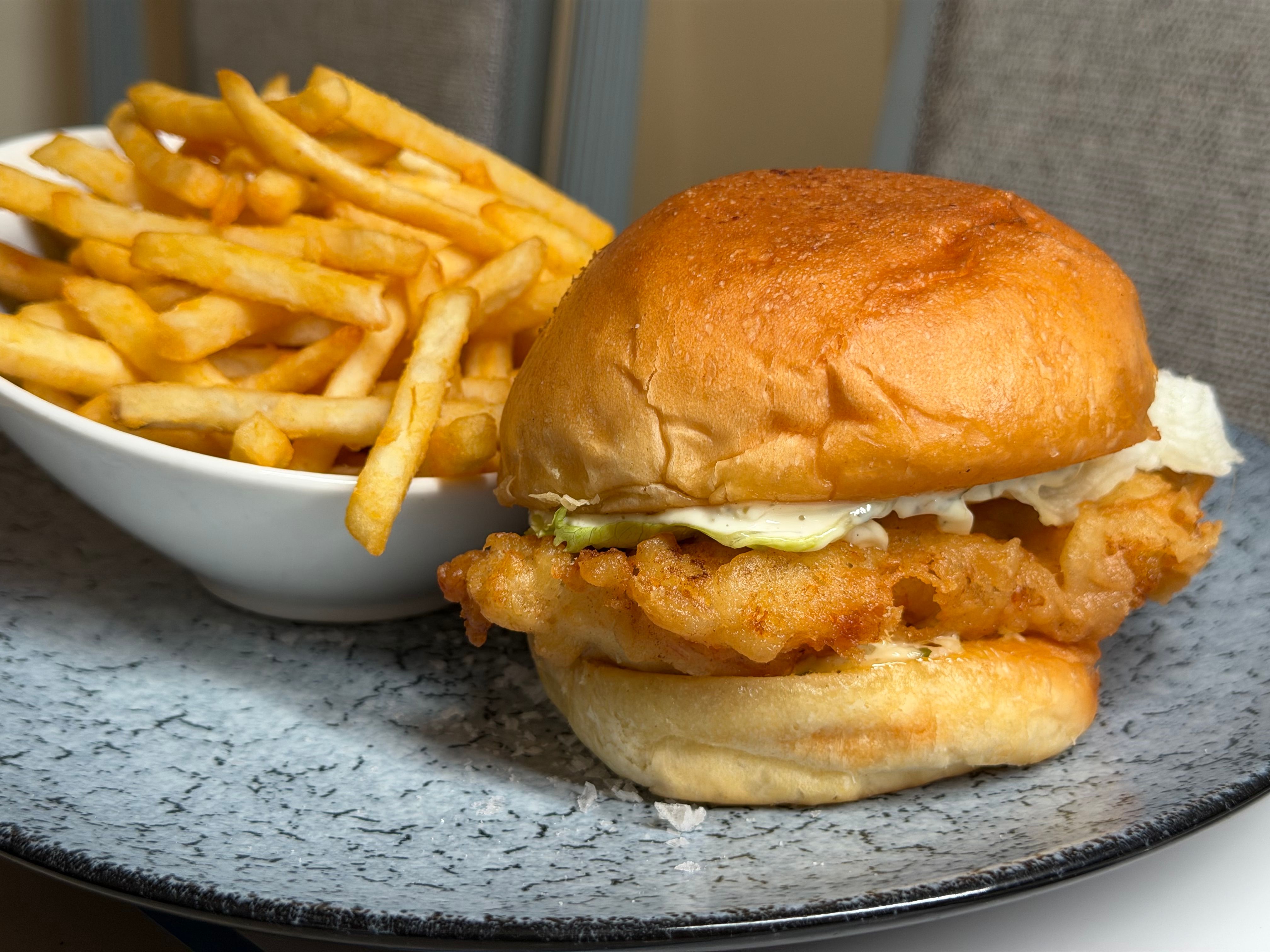 Delicious crispy fish sandwich served with a side of golden French fries on a stylish plate for a perfect meal. - Where to Eat Like a Local in Barbados: 10 Hidden Gems