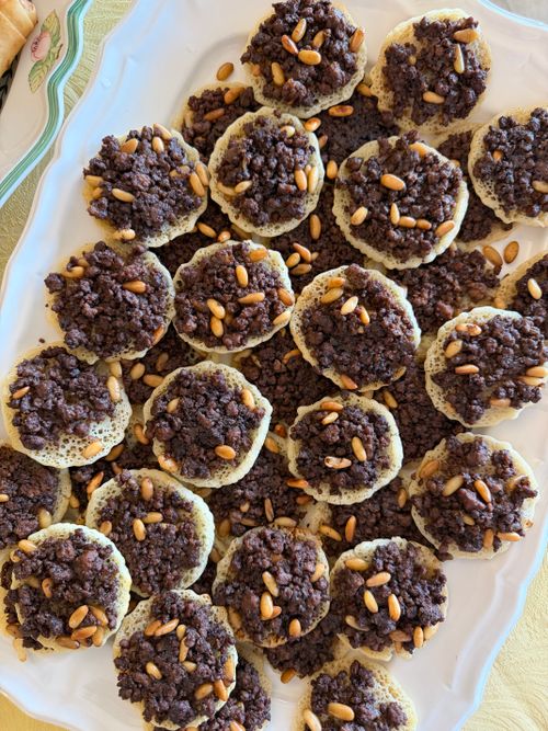 Free A close-up of traditional Lebanese Mana'eesh topped with pine nuts served on a white platter. Stock Photo