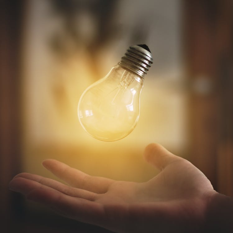 Light Bulb Floating Above Person's Hand