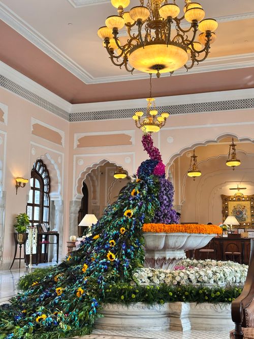 Free Opulent floral arrangement depicting a peacock in a lavish indoor setting under a grand chandelier. Stock Photo