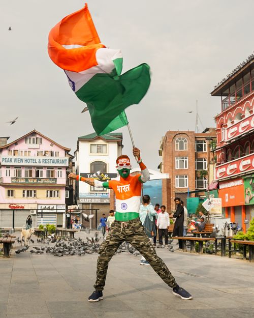 Free A person energetically waves the Indian flag in a lively city setting, expressing national pride. Stock Photo