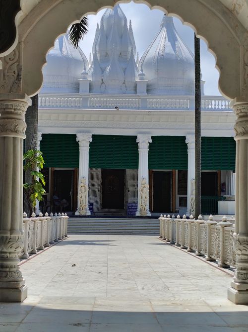 Free Elegant marble temple entrance with intricate carvings and domes, framed by an archway. Stock Photo