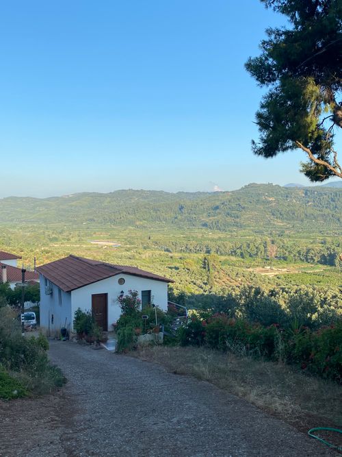 Free Beautiful view of a Greek countryside house with lush mountains in the background at sunrise. Stock Photo