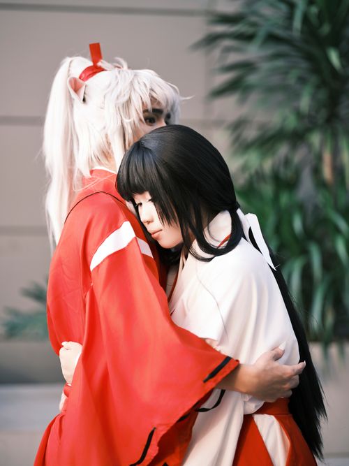 Free A touching moment between two cosplayers in red and white traditional costumes, embodying anime characters. Stock Photo