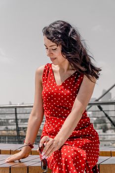 Stylish woman in red polka dot dress enjoying a sunny day in Baku.