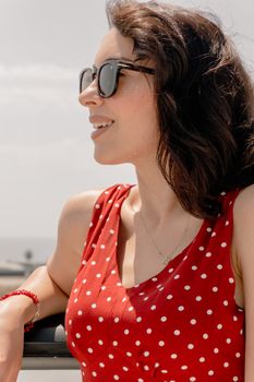 Joyful woman in red polka dot dress enjoying a sunny day in Baku, Azerbaijan.