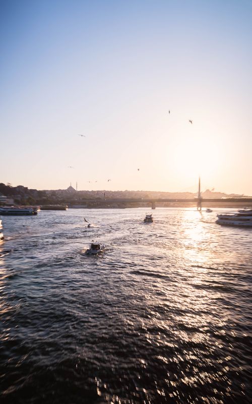 Free Scenic view of boats on the Bosphorus during sunrise with city skyline in the background. Stock Photo