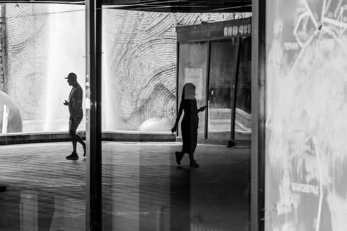 Free Black and white silhouette of people walking in a modern urban setting with architectural details. Stock Photo