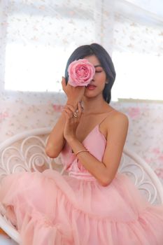 室内，一位穿着粉红色礼服的女子捧着鲜花的优雅肖像