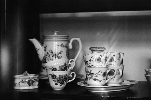Black and white photo of a vintage porcelain tea set on a shelf in Unna, Germany.