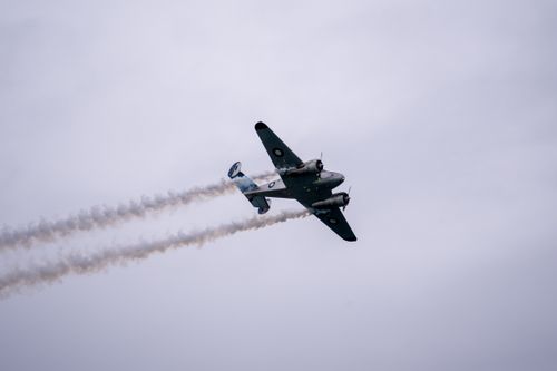 Free A classic vintage airplane soaring through overcast skies during an airshow. Stock Photo