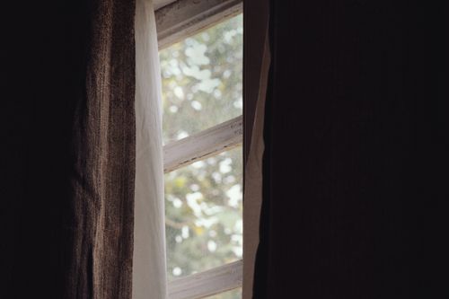 Free Soft natural light filters through a rustic window and curtain, creating a serene atmosphere. Stock Photo