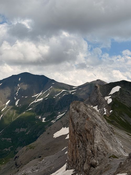 Free Panoramic view of the Caucasus Mountains with patches of snow under a cloudy sky. Stock Photo