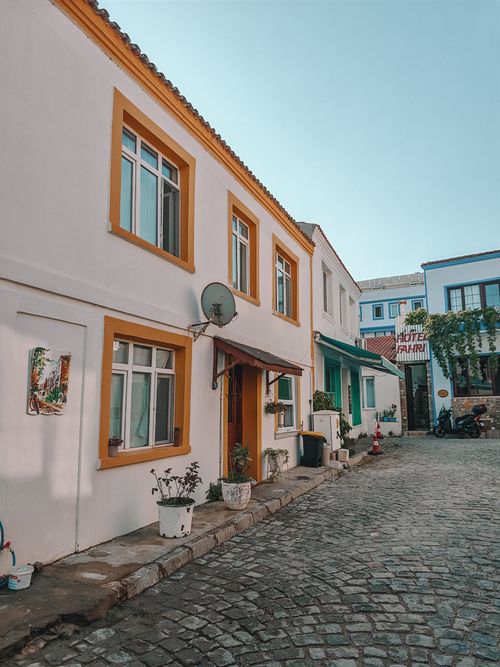 Free Cobblestone street lined with vibrant houses and potted plants in a quiet European neighborhood. Stock Photo