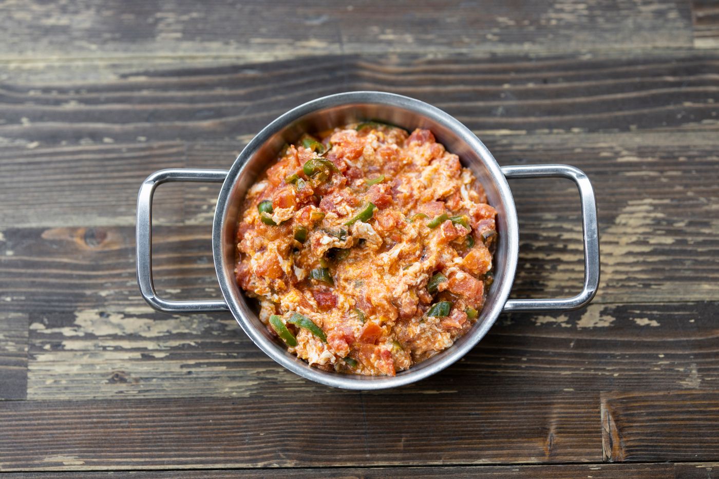 Colorful vegetarian scramble served in a metal pot on rustic wooden table.