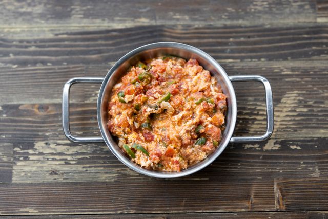 Colorful vegetarian scramble served in a metal pot on rustic wooden table.