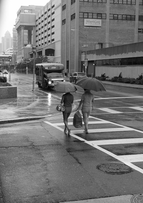 Grayscale Photo Of People Crossing The Road With Umbrella