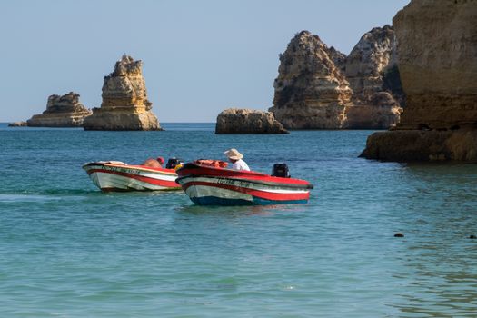 Colorful boats navigating near rocky cliffs on a sunny day, perfect for travel and adventure imagery.