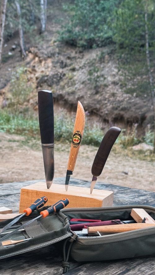 Free Set of wood carving knives displayed on a wooden block outdoors in a forest setting. Stock Photo