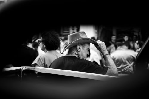 Free A cowboy wearing a hat, standing in a busy crowd, captured in black and white. Stock Photo