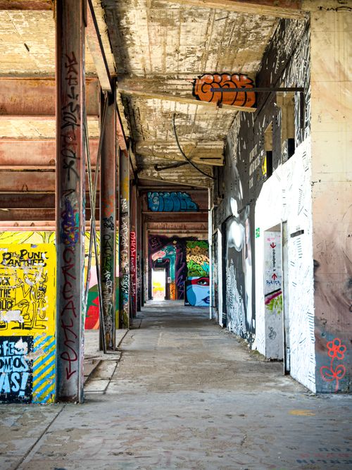 Free A colorful graffiti-covered corridor in an abandoned urban building, showcasing street art and decay. Stock Photo