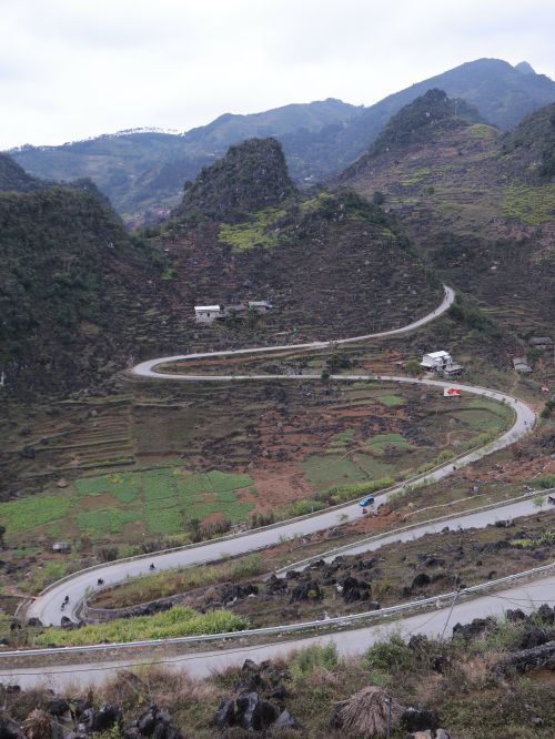 Free Aerial view of a winding road through mountain landscape with lush green fields. Stock Photo