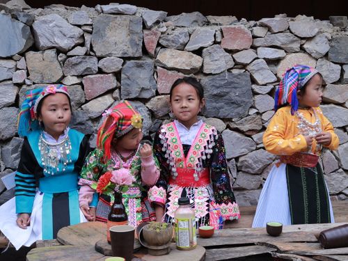 Free Group of children in colorful traditional clothing outdoors against a stone wall. Stock Photo