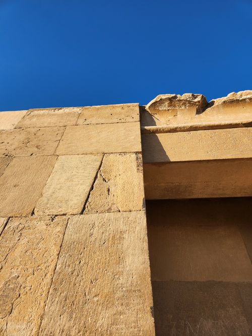 Free Close-up of a textured, weathered stone structure under a clear blue sky. Stock Photo