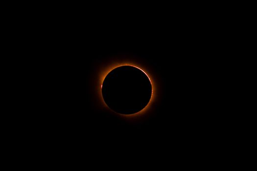 Stunning solar eclipse viewed in the night sky, captured in Spain with vibrant orange corona.